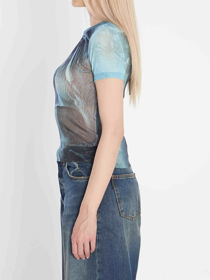 Person wearing a blue t-shirt with a graphic design and jeans on a white background