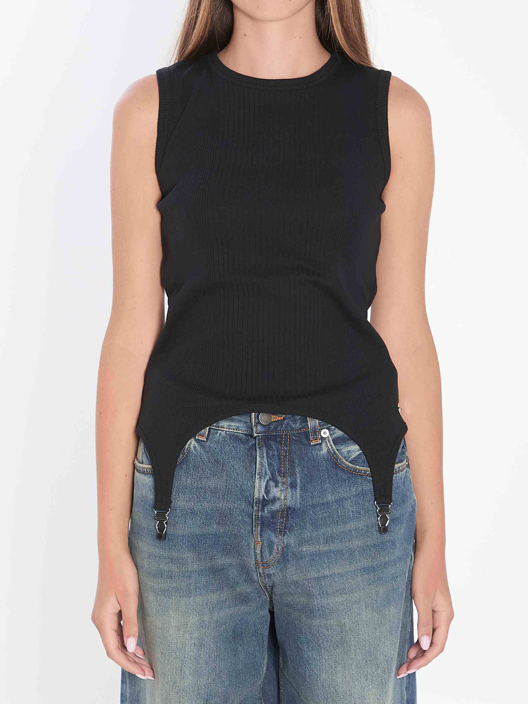 Person wearing a black sleeveless top and blue jeans on a white background