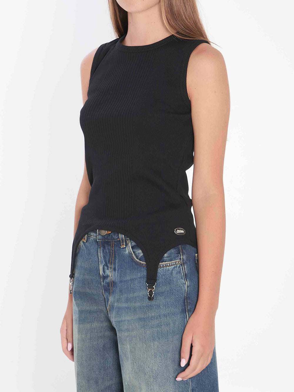 Person wearing a black sleeveless top and blue jeans on a white background