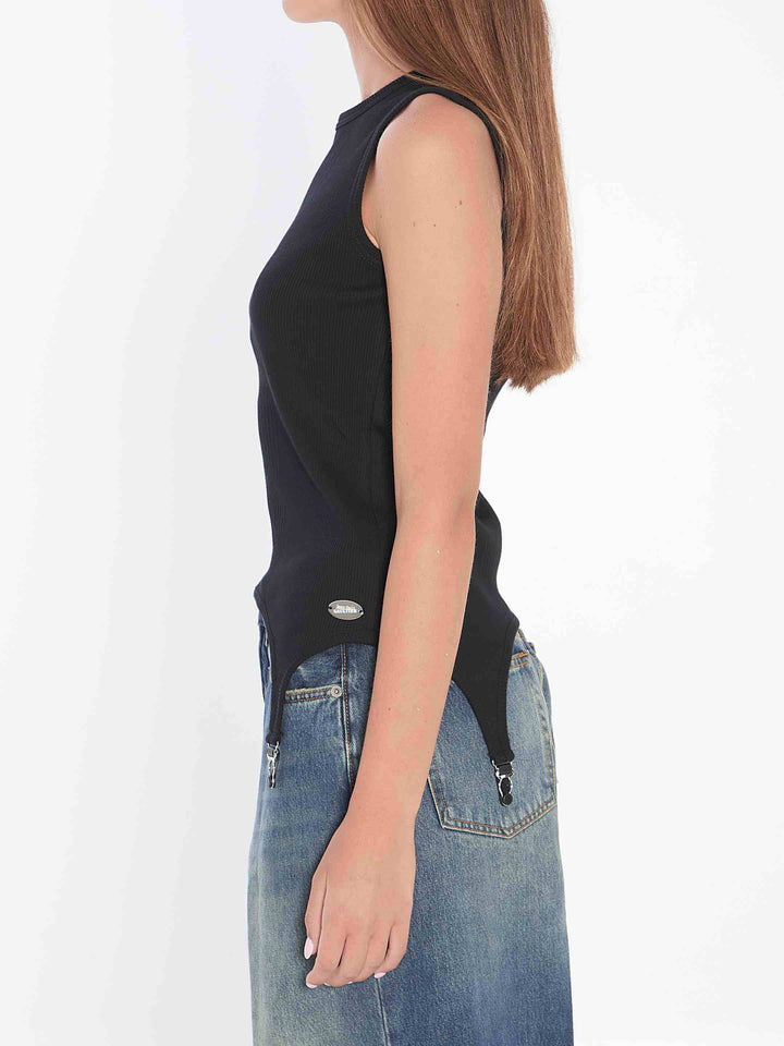 Person wearing a black sleeveless top and blue jeans on a white background