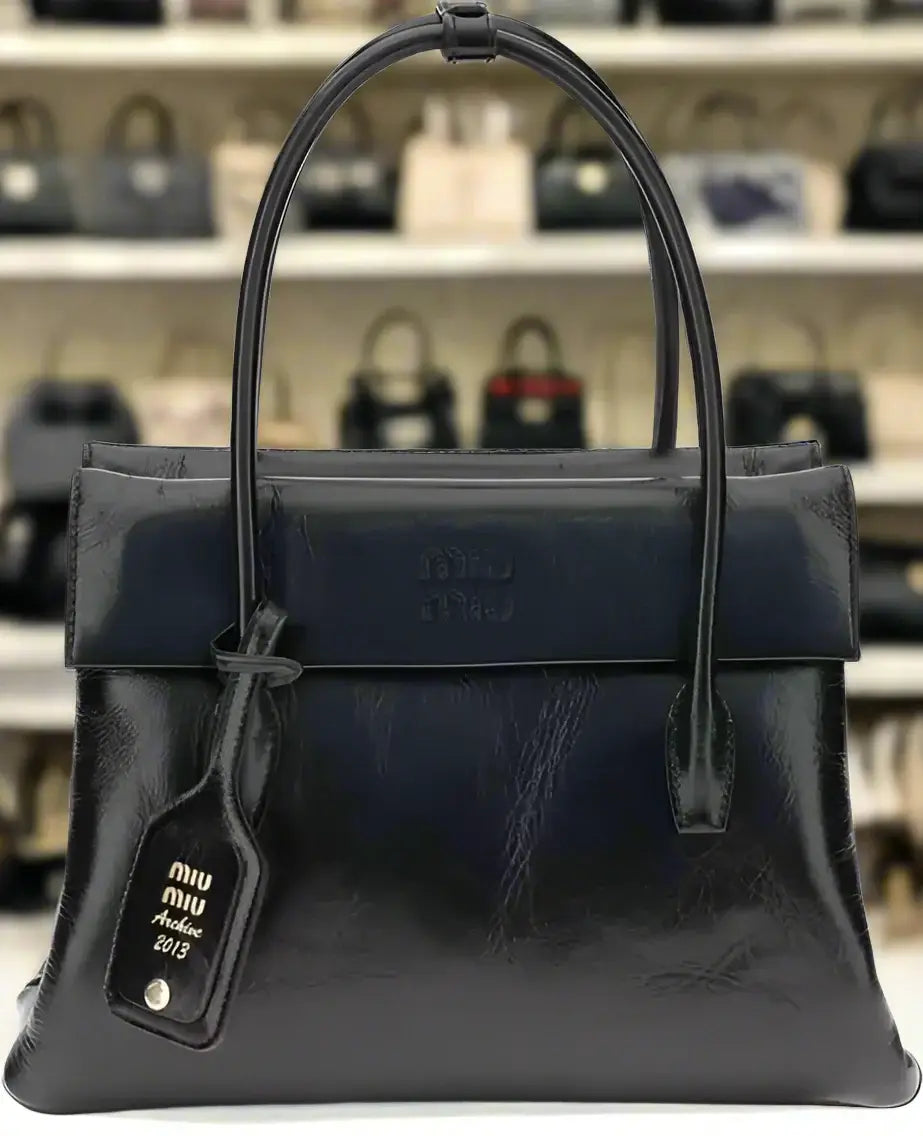 Black leather handbag with 'miu miu' tag on a white background