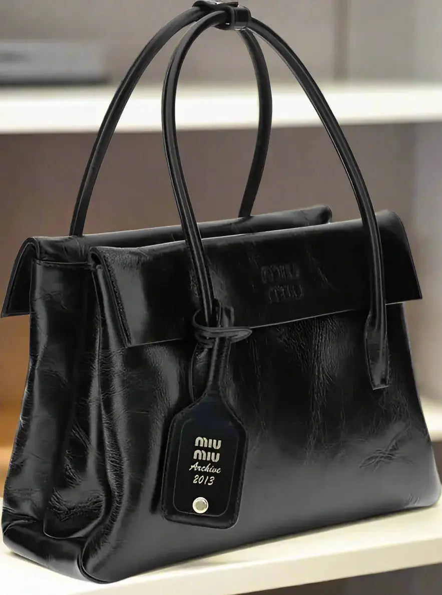 Black leather handbag with a visible brand tag on a white background