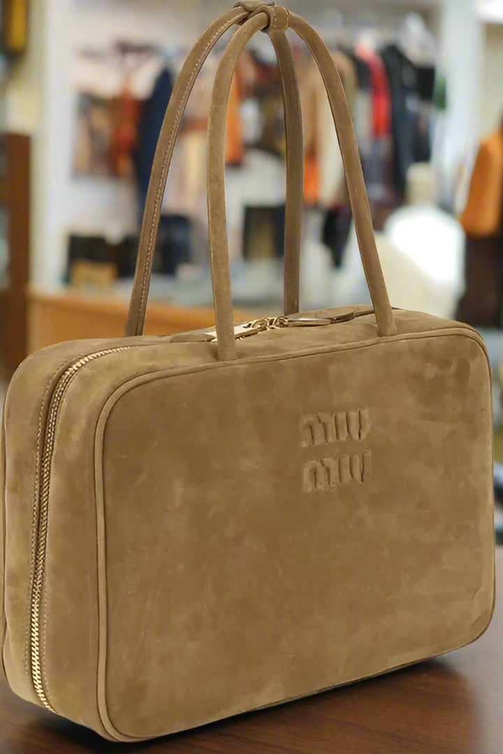 Brown leather bag with 'miu miu' logo on a white background