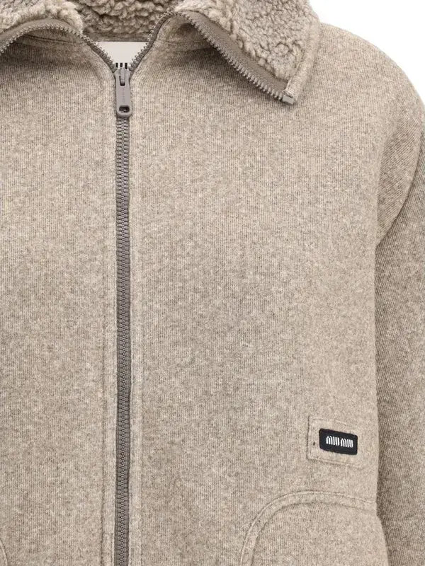 Close-up of a beige fleece jacket with a brand label on the chest.