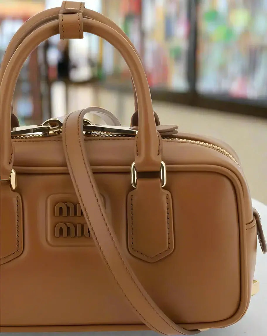 Brown handbag with gold accents on a white background
