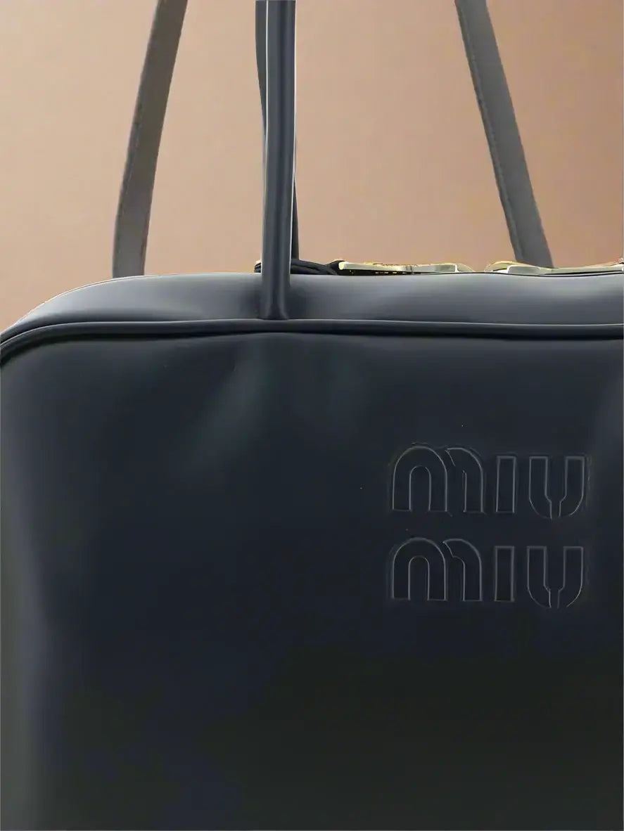 Black handbag with 'Miu Miu' logo on a white background