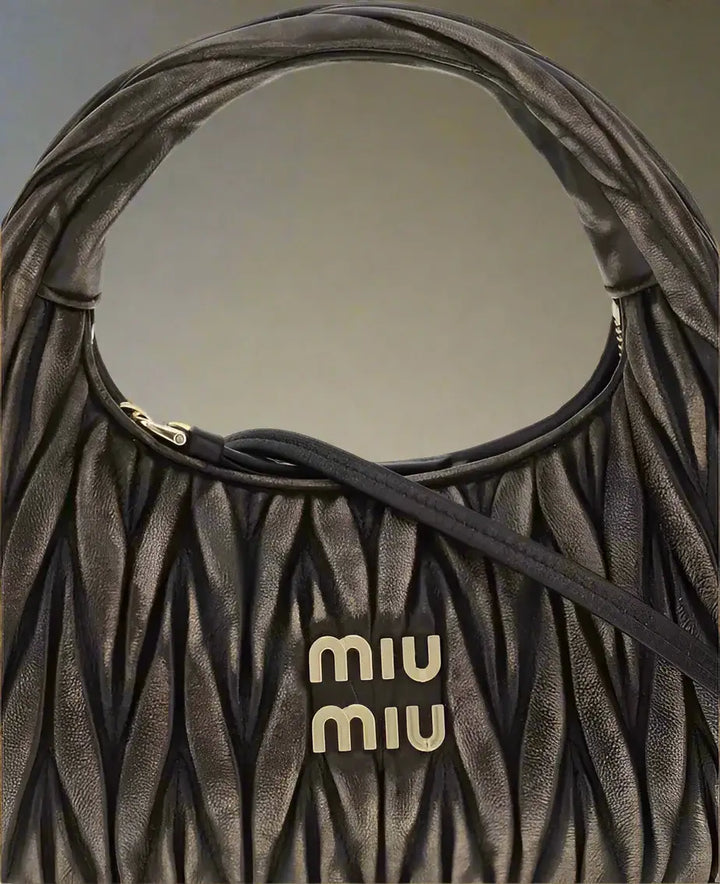 Brown textured handbag with 'MIU MIU' logo on a white background