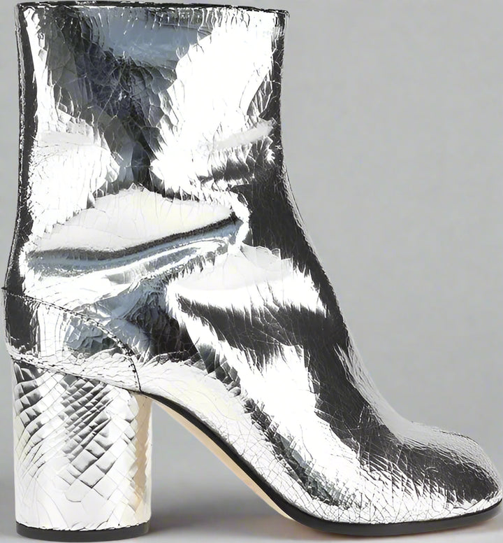 Silver metallic ankle boot with a block heel on a white background