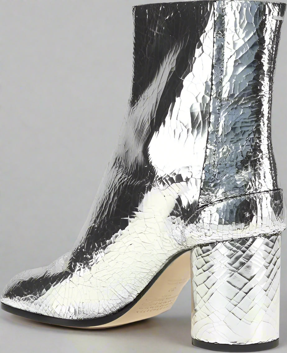 Silver metallic ankle boot with a block heel on a white background