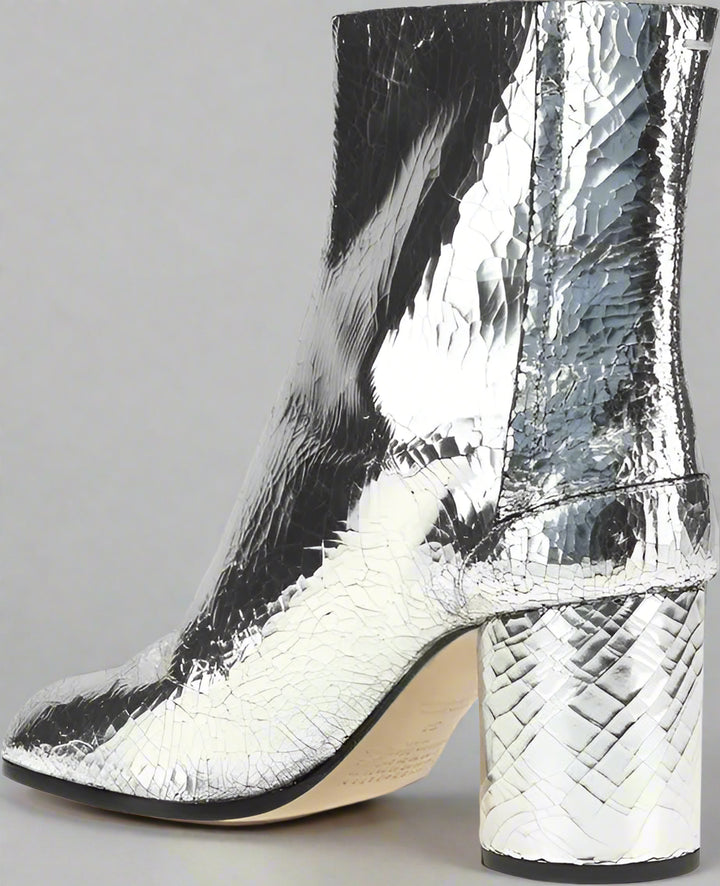 Silver metallic ankle boot with a block heel on a white background
