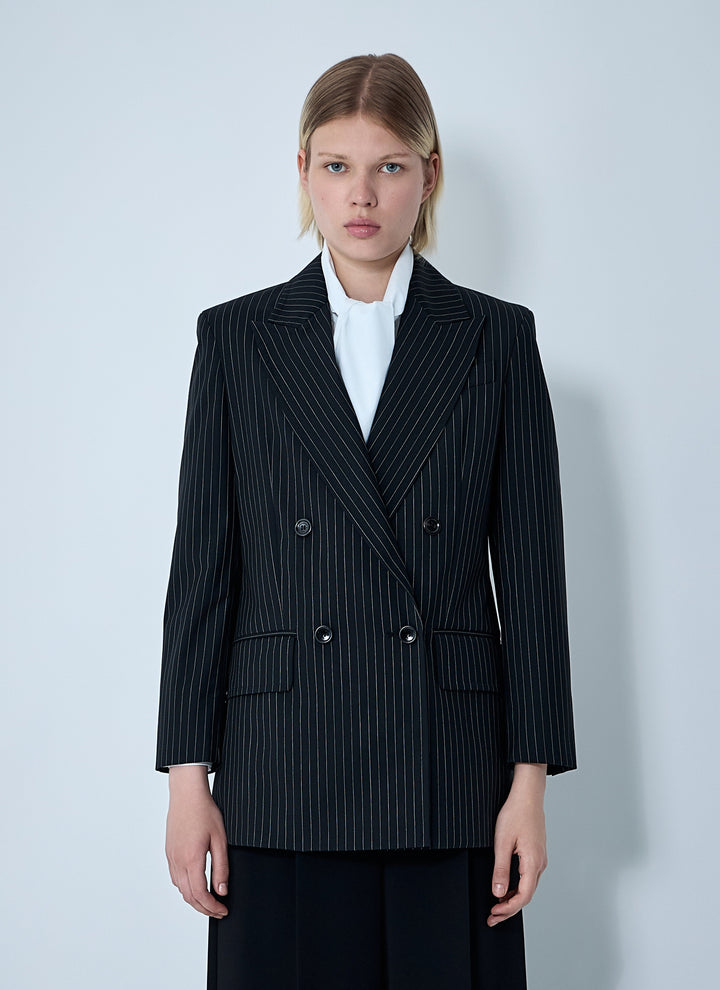 Woman wearing a black pinstripe blazer over a white shirt on a light gray background