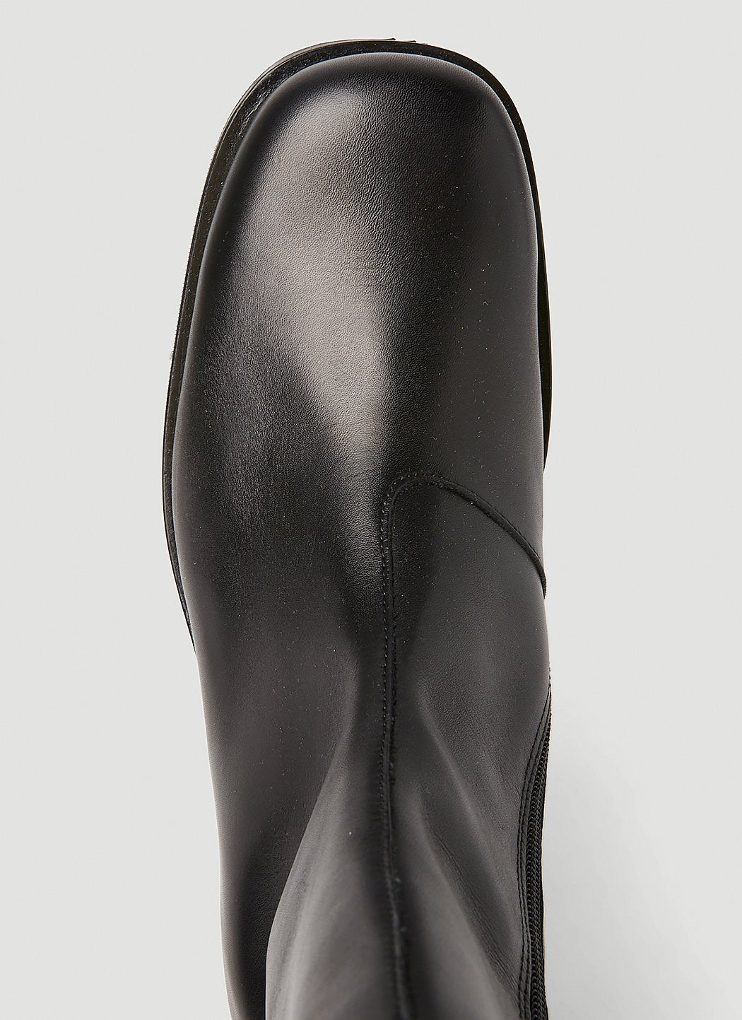 Black leather boot on a light gray background