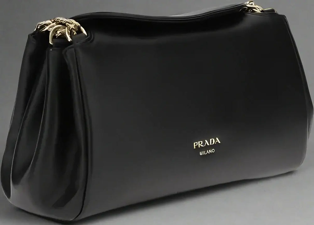 Black Prada handbag with gold hardware on a white background