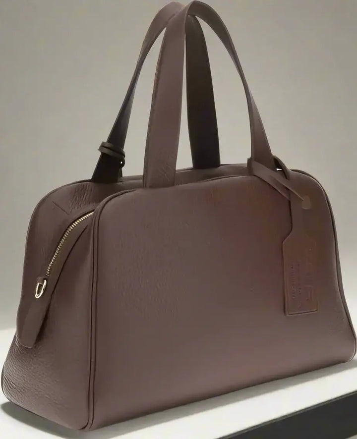 Brown leather bag with a visible brand tag on a white background