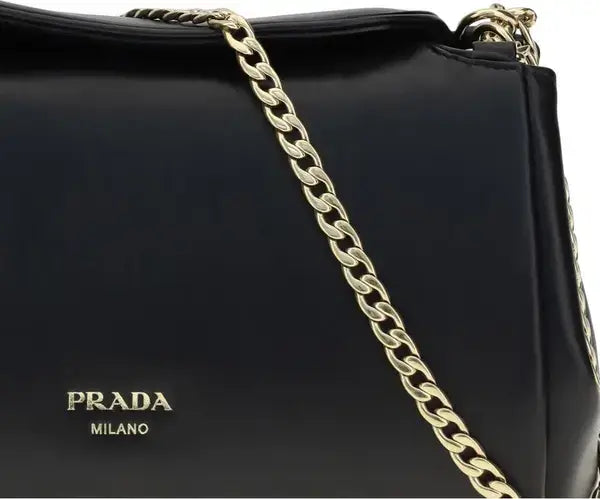 Black Prada handbag with a gold chain strap on a white background