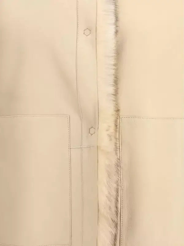 Close-up of a beige jacket with a fur-lined hood and button details.