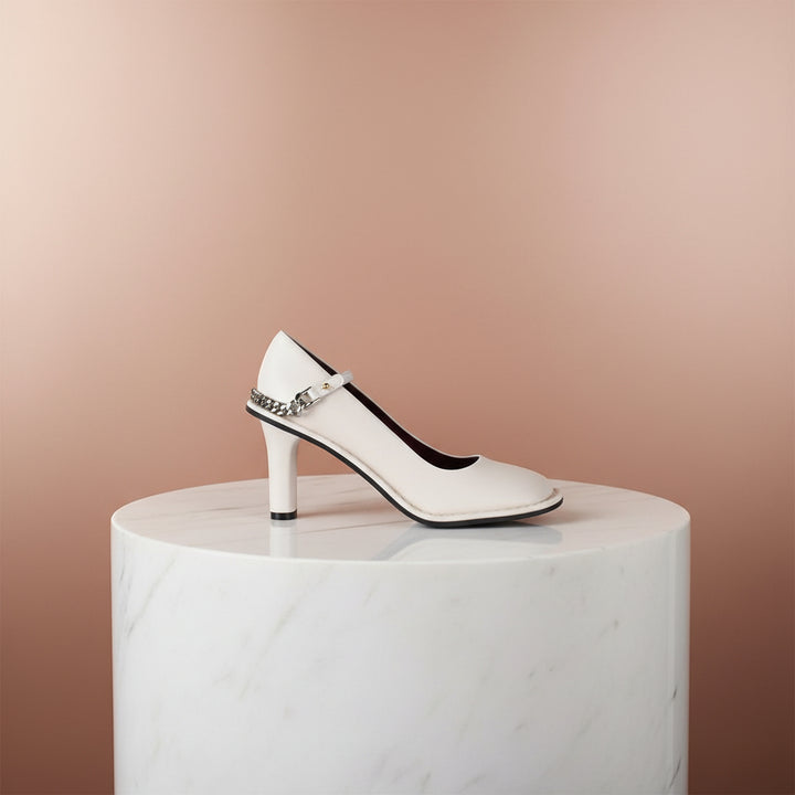 White high-heeled shoe with chain detail on a white background
