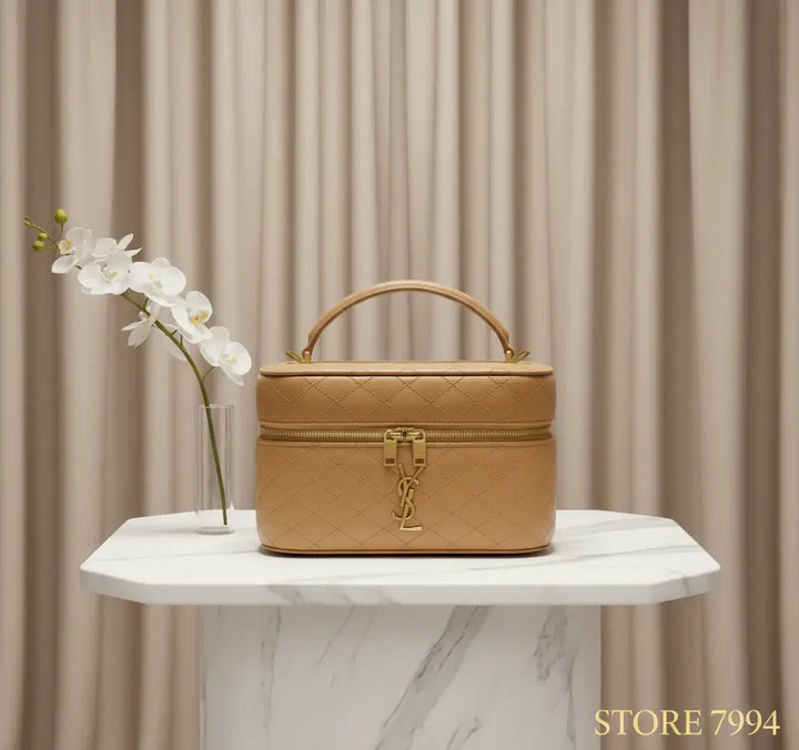 Beige quilted leather travel case with gold zipper and logo on a white background