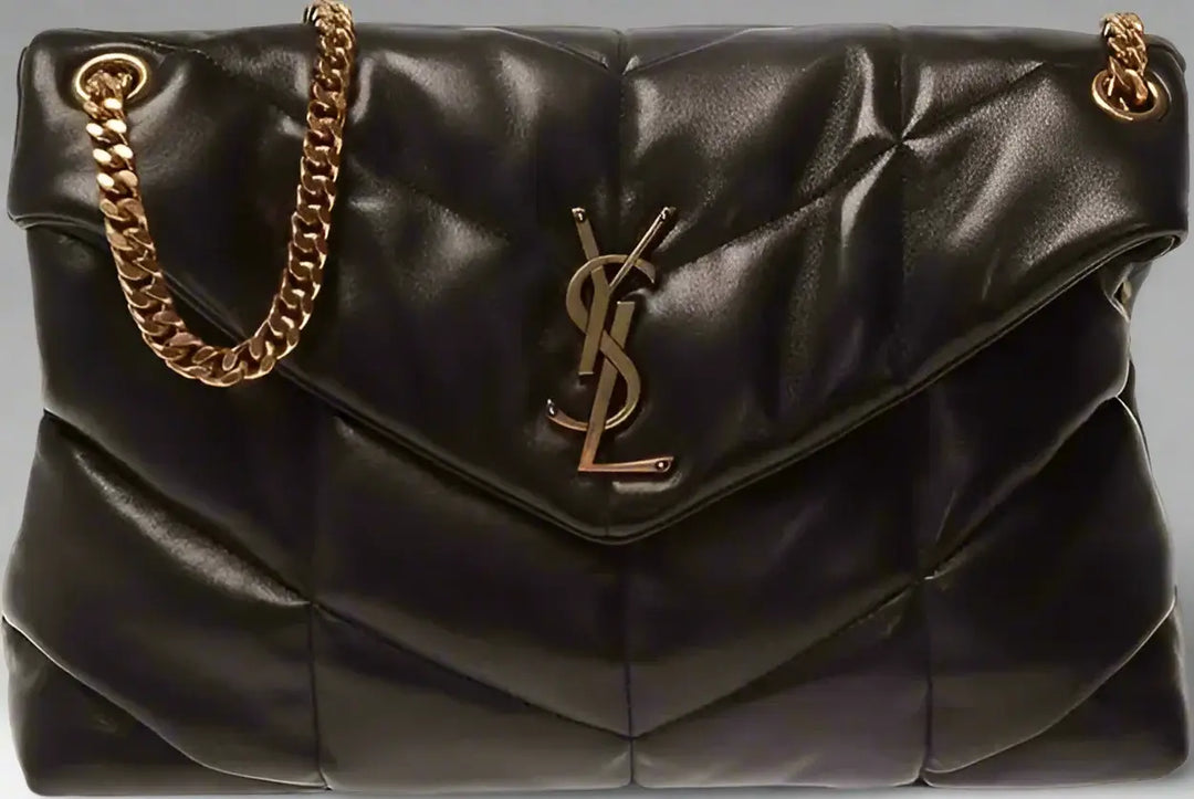 Black quilted handbag with gold chain and logo on a black background