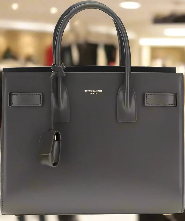 Black handbag with 'Saint Laurent' branding on a white background