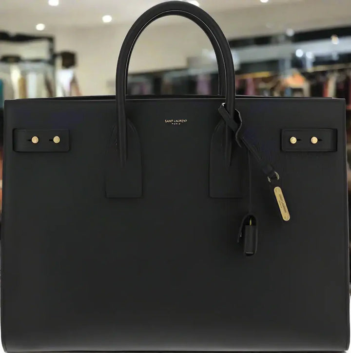 Black handbag with gold hardware on a white background