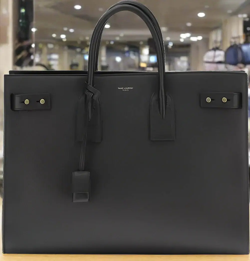 Black leather handbag with gold hardware on a white background