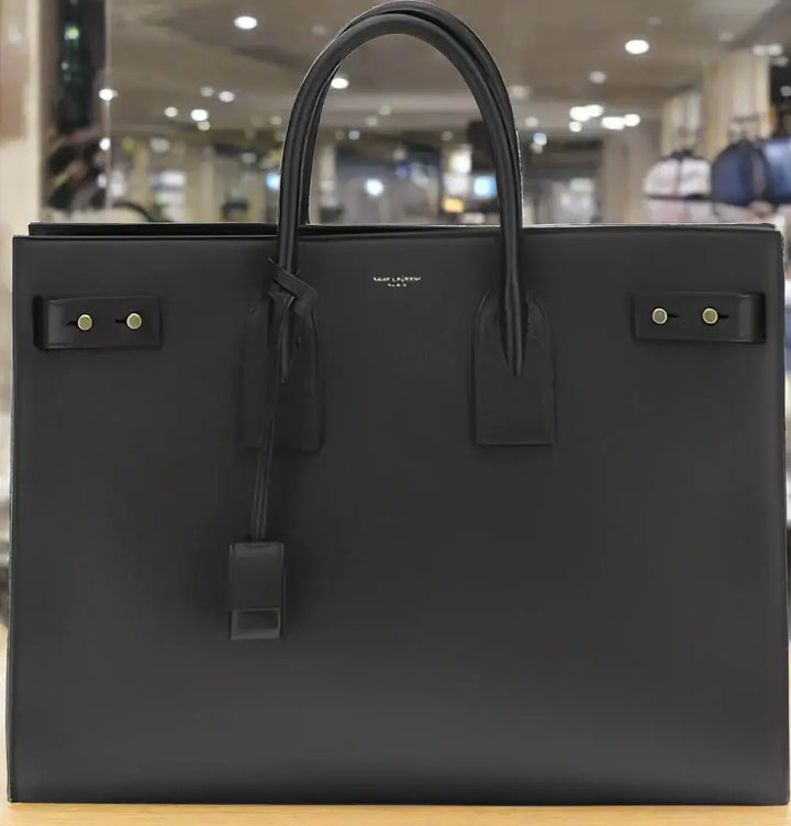 Black leather handbag with gold hardware on a white background