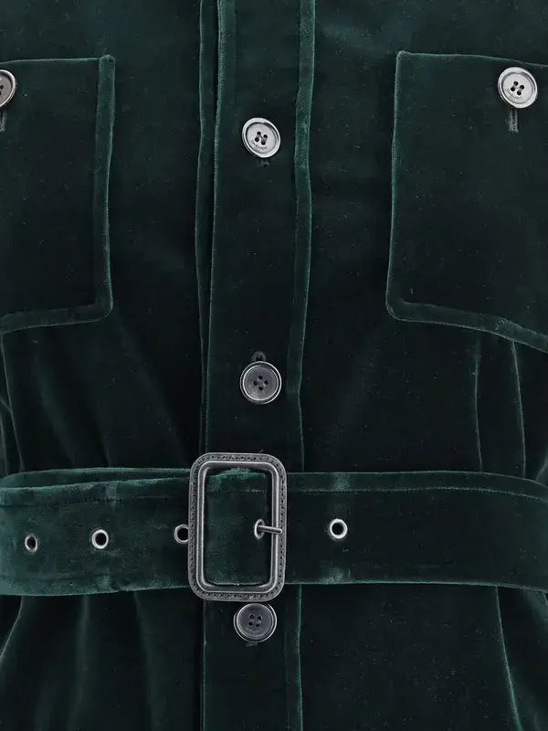 Close-up of a green velvet garment with buttons and a belt buckle.