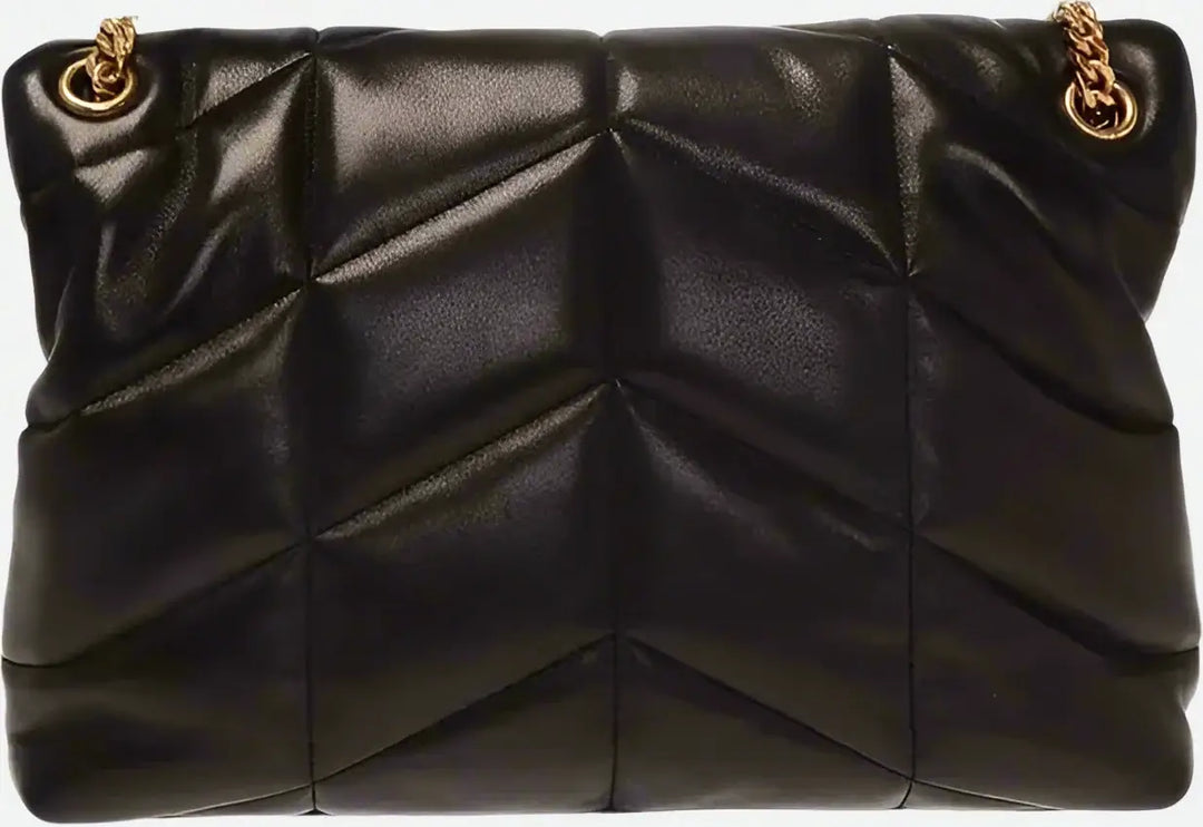 Black quilted handbag with gold chain strap on a black background