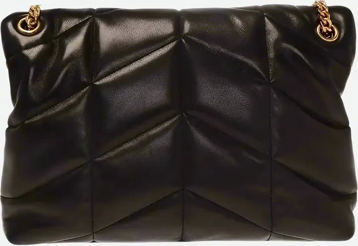 Black quilted handbag with gold chain strap on a black background