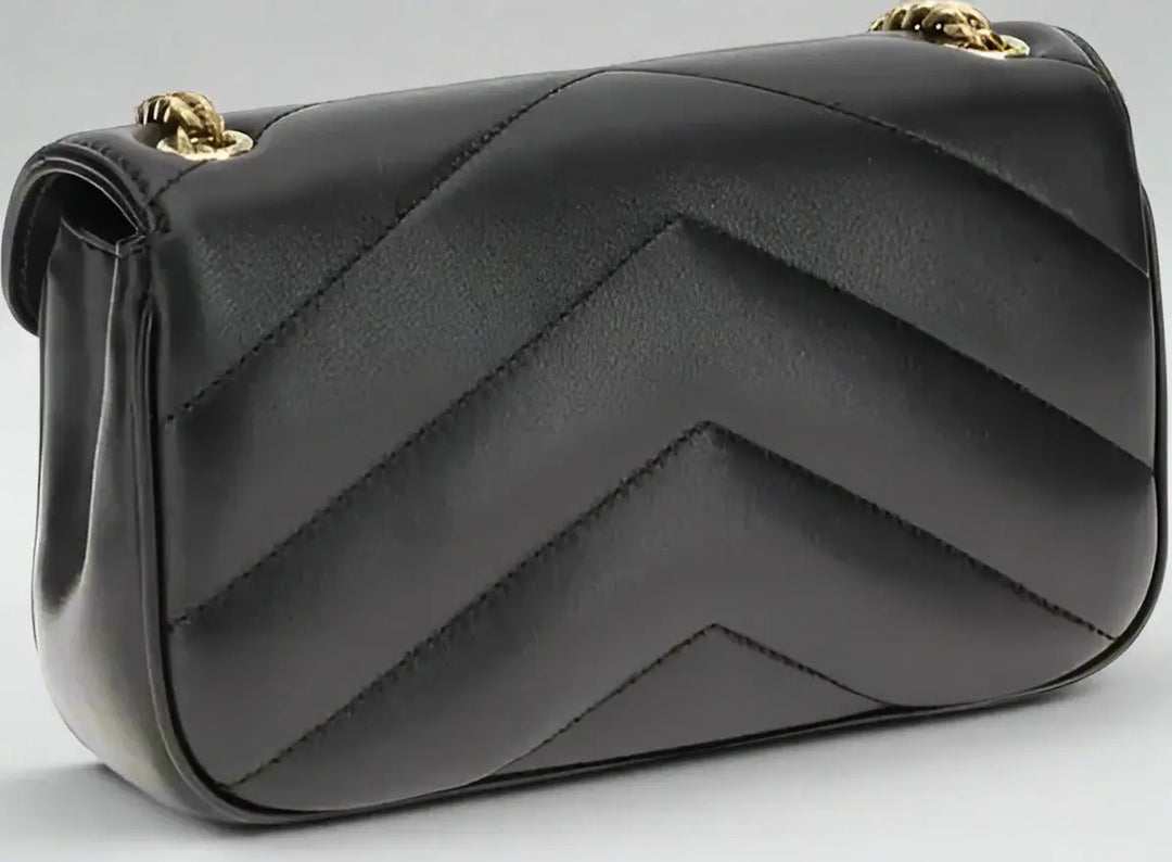 Black quilted handbag with gold accents on a white background