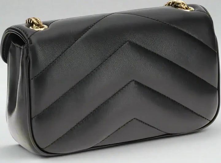 Black quilted handbag with gold accents on a white background