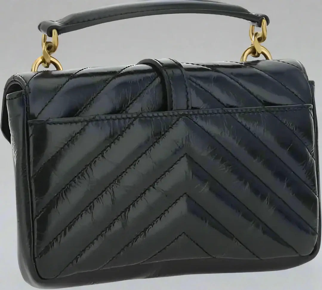 Black quilted handbag with gold handles on a white background