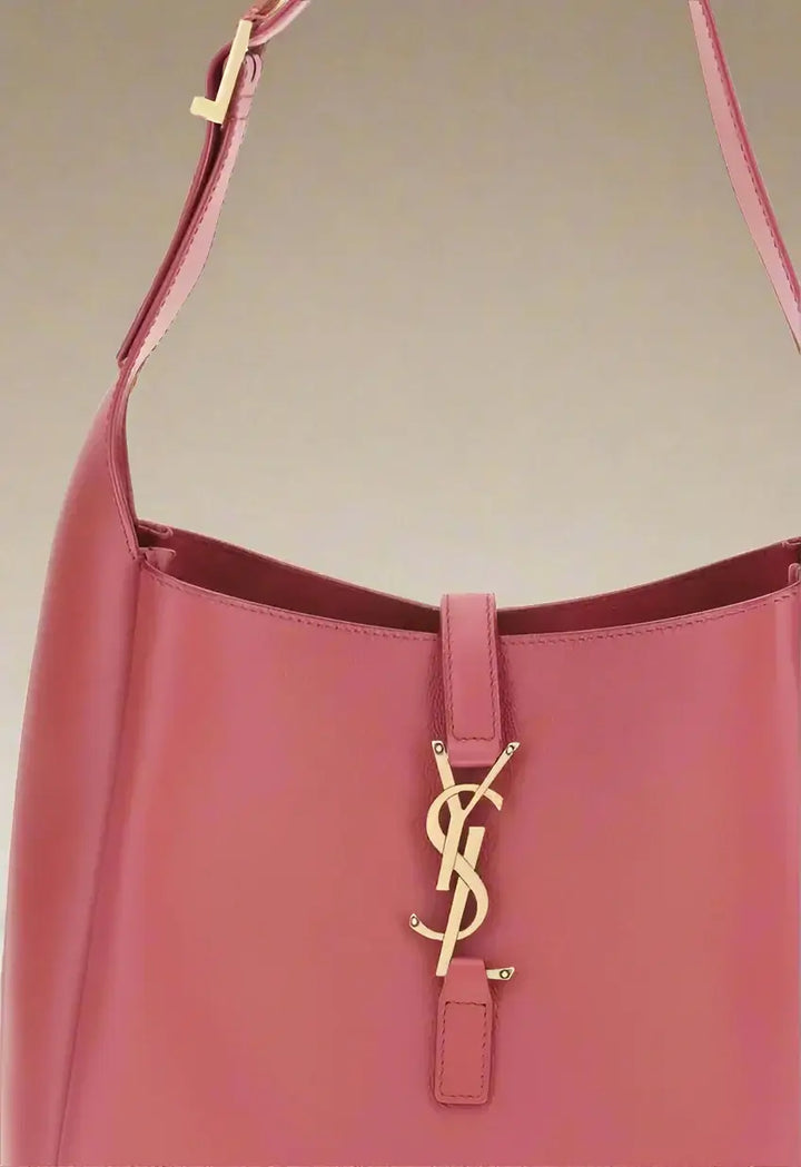 Pink handbag with a gold logo on a white background
