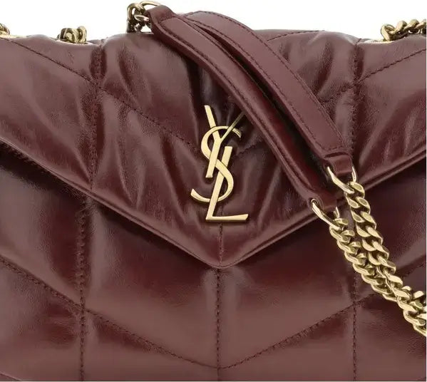 Maroon quilted handbag with gold chain and logo on a black background