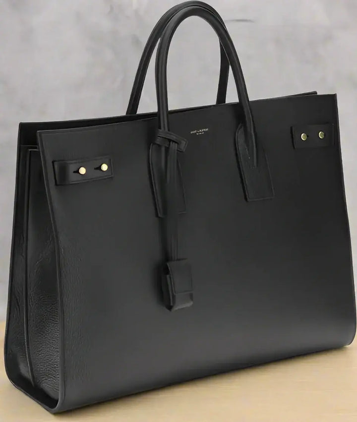 Black leather handbag with gold hardware on a white background