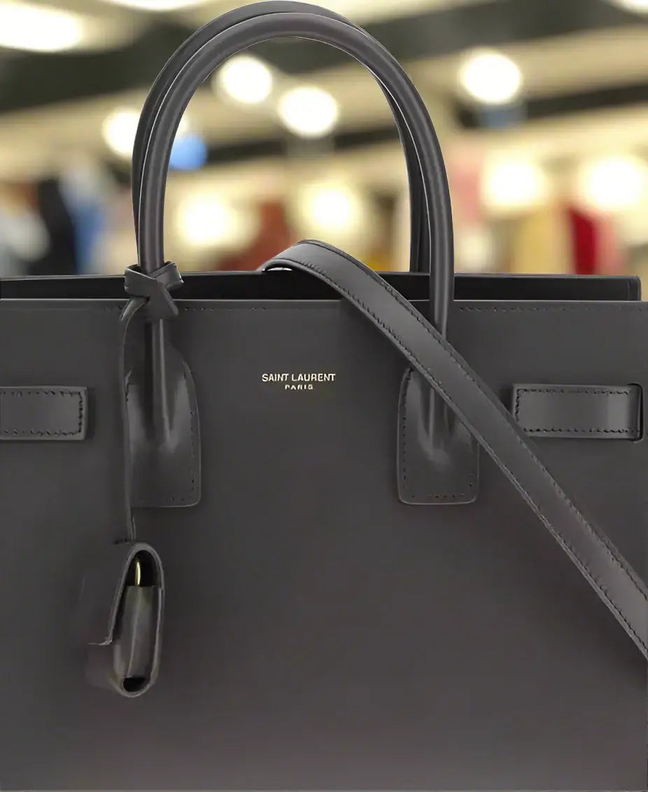 Black handbag with 'Saint Laurent' branding on a white background