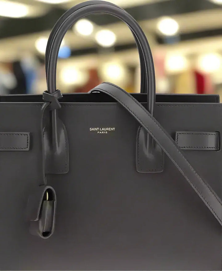 Black handbag with 'Saint Laurent' branding on a white background