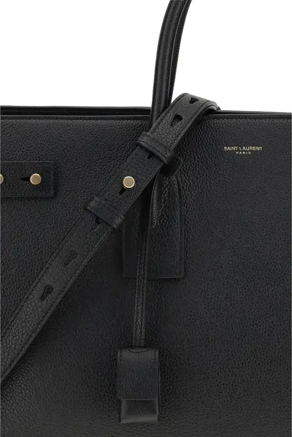 Black leather handbag with strap detail on a white background