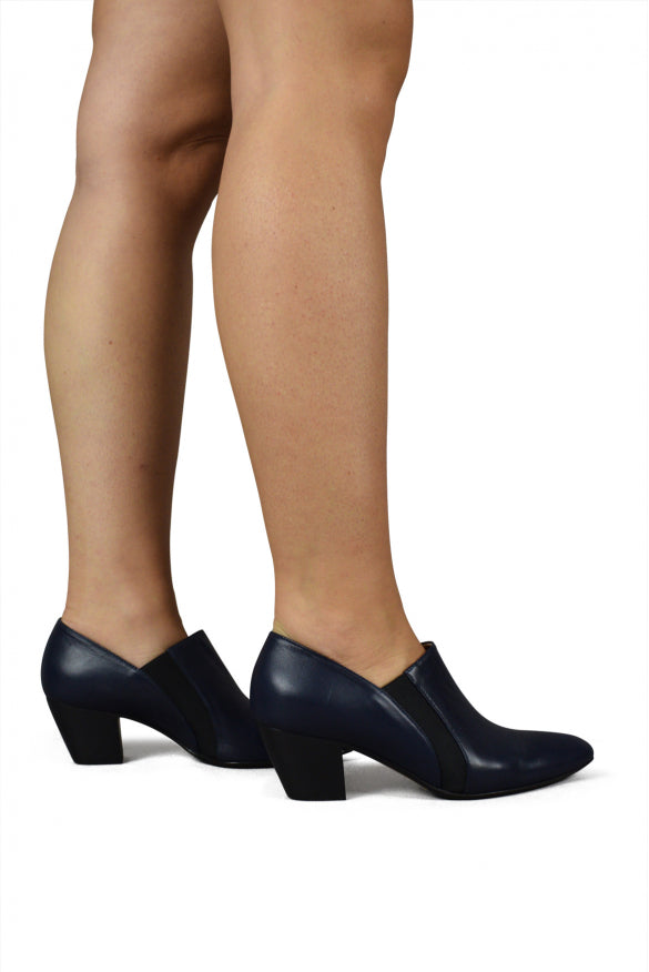 Navy high-heeled shoes worn with beige tights on a white background