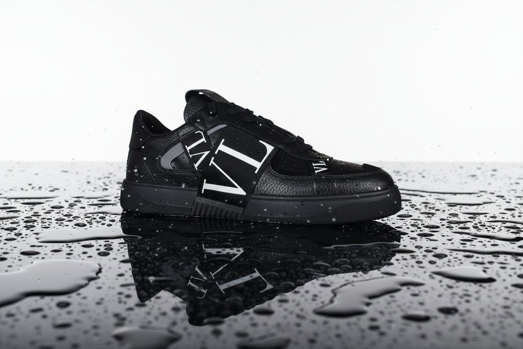 Black sneaker with a brand logo on a white background