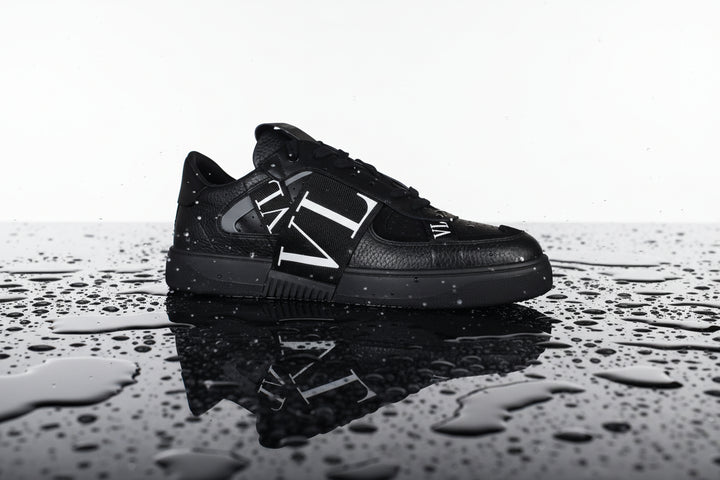 Black sneaker with a brand logo on a white background