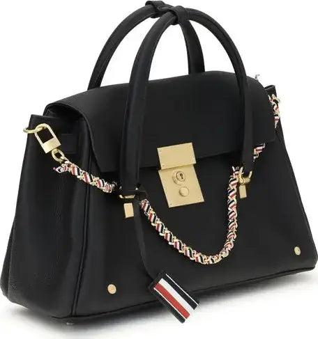 Black handbag with gold accents and a decorative strap on a white background