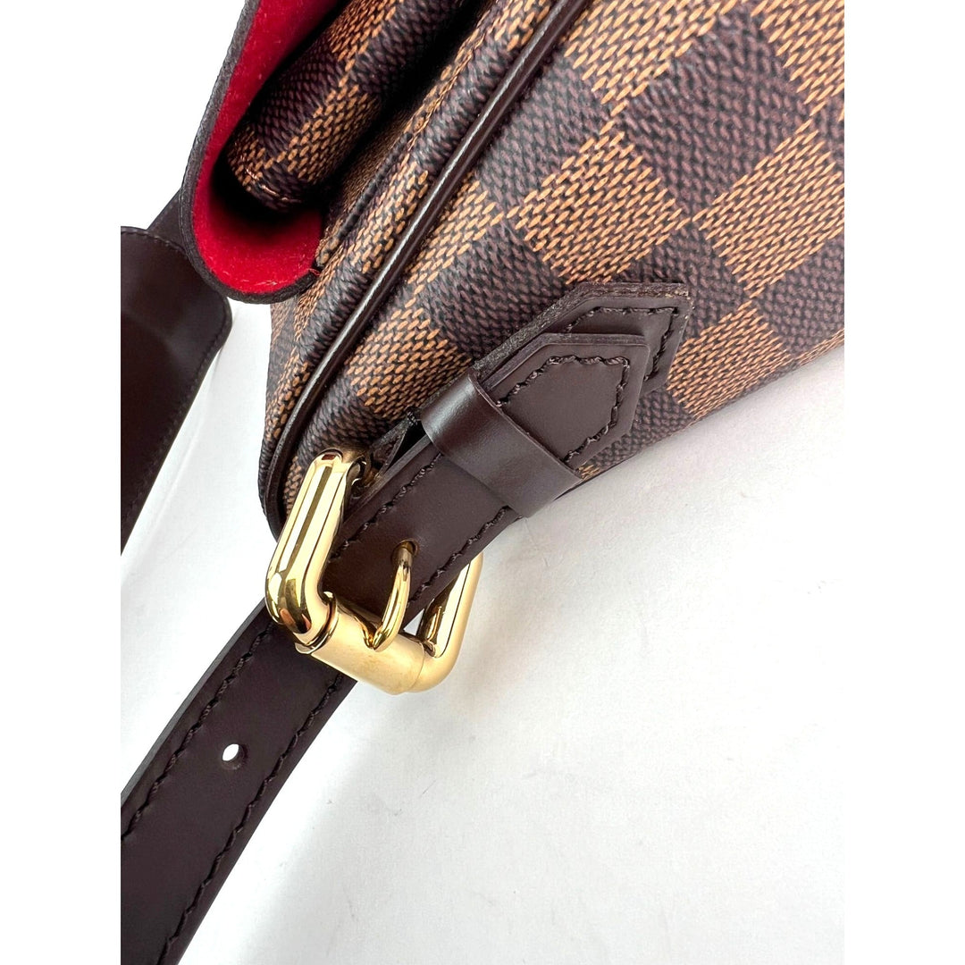 Close-up of a brown checkered handbag with gold buckle on a white background