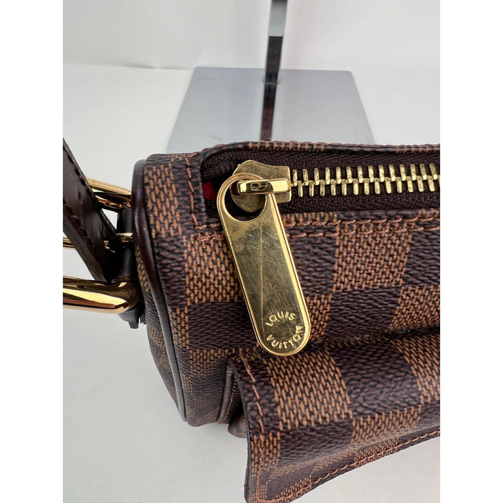 Close-up of a brown checkered handbag with gold zipper and hardware on a white background