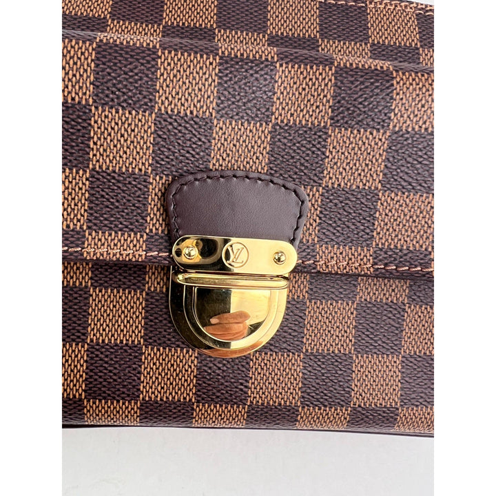 Close-up of a brown and black checkered handbag with a gold clasp on a white background