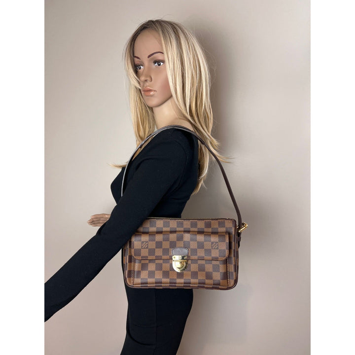 Woman holding a brown checkered handbag against a plain background