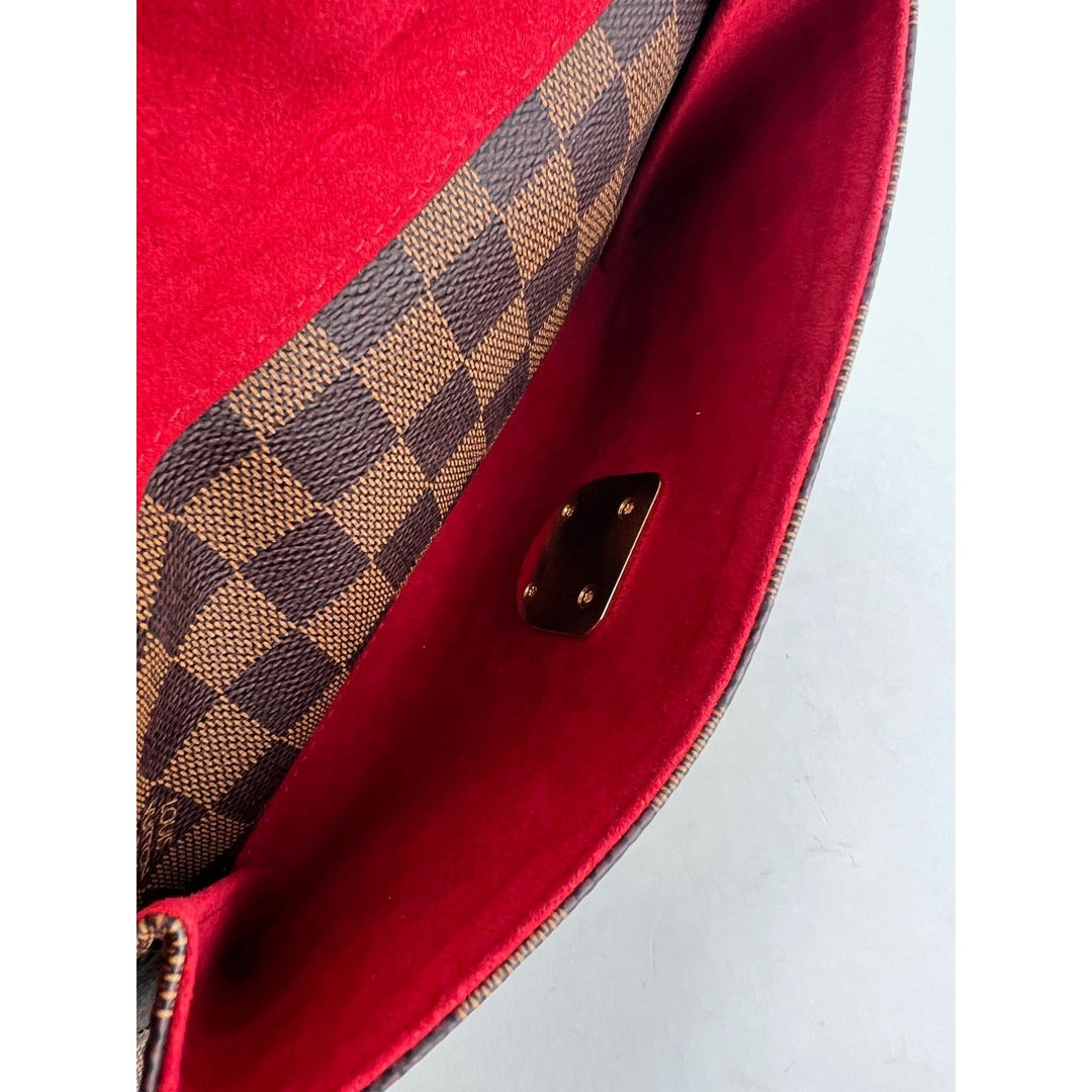 Close-up of a red handbag with brown checkered pattern on a white background