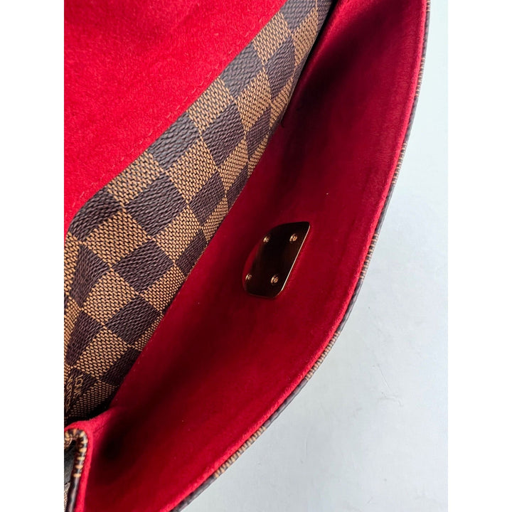 Close-up of a red handbag with brown checkered pattern on a white background