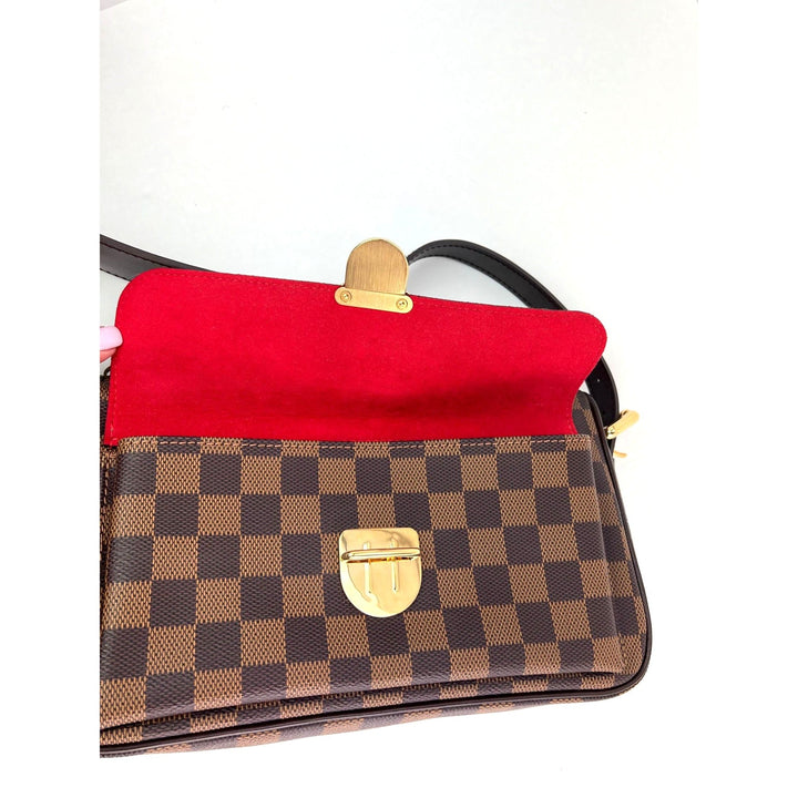 Designer handbag with red interior and gold hardware on a white background